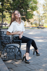 年轻的女孩坐在长凳上片秋色的公园