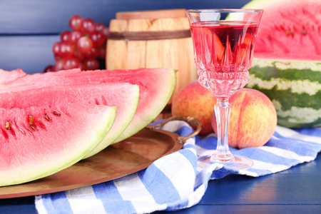 成熟的西瓜 水果 桃红葡萄酒玻璃和木桶上彩色木背景的组成