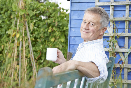 老人放松着杯咖啡的花园里
