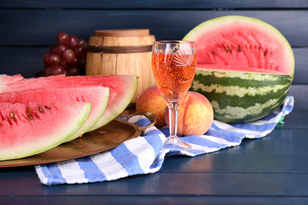 成熟的西瓜 水果 桃红葡萄酒玻璃和木桶上彩色木背景的组成