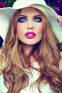 美丽 时尚 金发碧眼的女郎模型与亮妆和粉红色的嘴唇与完美的清洁肌肤，在帽子里附近夏花之绚烂的高级时装 look.glam