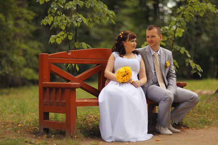 新娘和新郎坐在长凳上