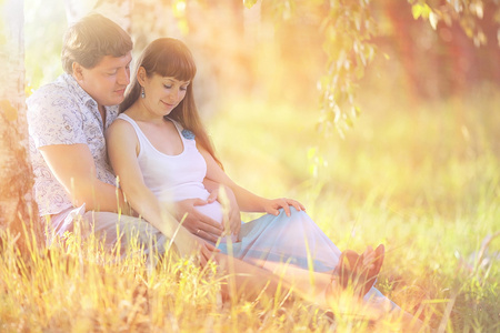 男人和一个怀孕的女人躺在草地上
