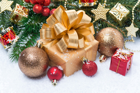 黄金礼品盒和圣诞装饰品在雪中