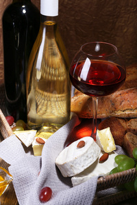 晚饭组成的卡门培尔奶酪和干酪奶酪 蜂蜜 葡萄酒和葡萄在餐巾纸放在木制的桌子上棕色背景上篮