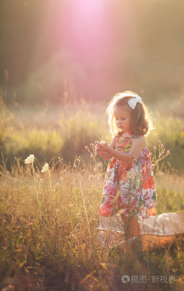 小女孩站在田野上保持双手合十在童话夕阳光