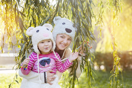 妈妈和女儿在公园里，在微笑熊针织帽