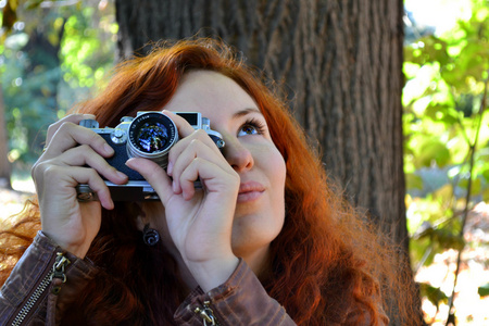 年轻的红发女子与复古相机拍照