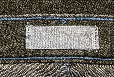 灰色棕色牛仔裤背景的空白灰色纺织标签