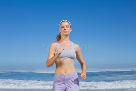 运动型金发女郎在海滩上慢跑