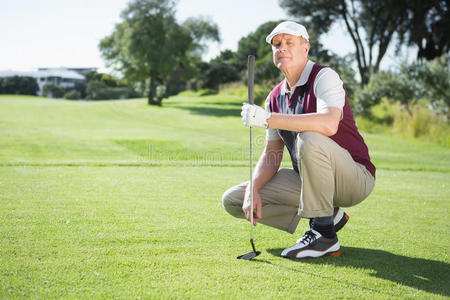 自信的高尔夫球手跪着拿着他的高尔夫球杆