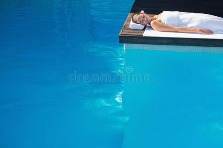 安静的黑发女人闭着眼睛躺在毛巾池边