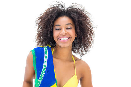 穿着黄色比基尼的合适女孩拿着巴西国旗对着相机微笑