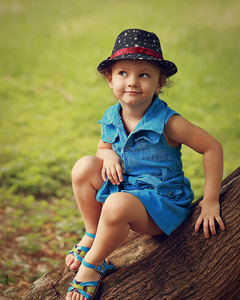 可爱有趣的小女孩戴着帽子和时尚的蓝色连衣裙