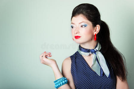 复古风格的漂亮女孩，蓝色西装配上鲜艳美丽的红唇妆，正在工作室的蓝色背景上