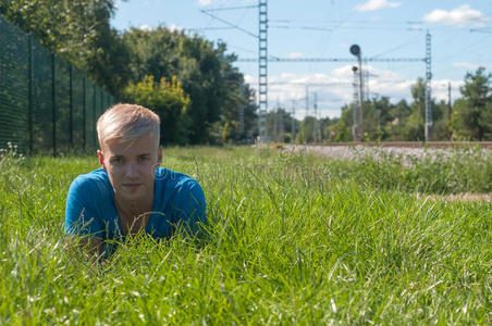 一个穿蓝色衣服的年轻人躺在绿色的草地上