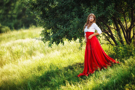 穿着红裙子的女人站在树下
