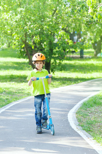 男孩站在公园的小路上用脚踏车