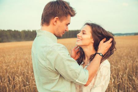 相爱的年轻夫妇户外.情侣拥抱。年轻美丽的情侣在夕阳下停留在田野上亲吻。