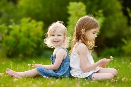 两个可爱的小妹妹坐在草地上