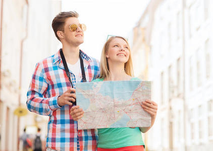 一对微笑的夫妇带着地图和照相机在城市里