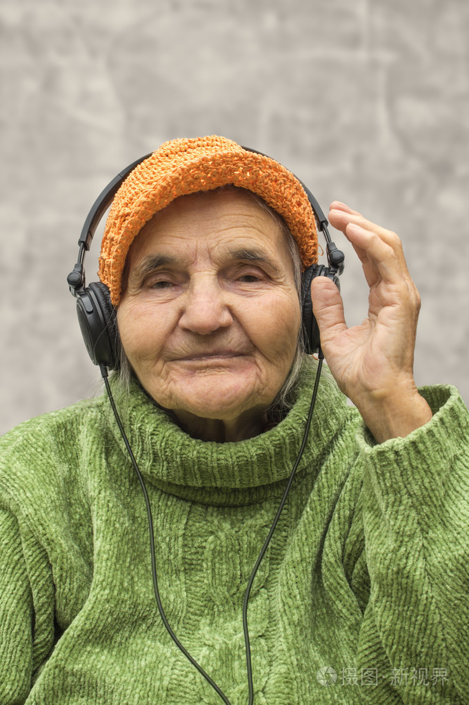 老年妇女戴着耳机听音乐
