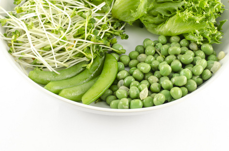 在白色背景上分离出的白盘子里的绿色蔬菜