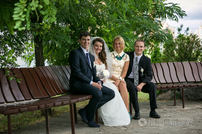 已婚夫妇和两名证人在公园的长椅上坐着