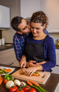 夫妇拥抱和准备在厨房里的蔬菜