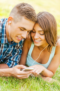 对夫妇躺在草地上，然后选择手机上的音乐