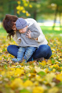 快乐的年轻母亲与她的小宝贝片秋色的公园