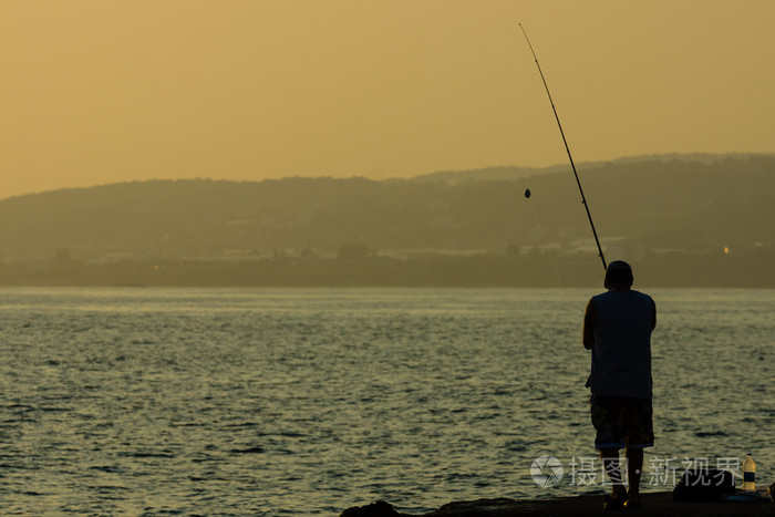孤独的渔夫从岸上钓鱼.