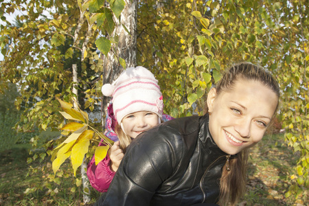 年轻的母亲和她的女儿在秋天