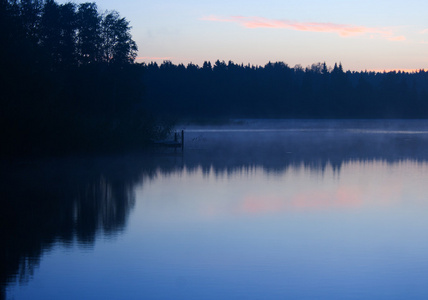 早晨的自然雾蒙蒙的景象景观湖岸或河流的天空和森林树木，通过光雾雾和水面上的倒影可见。 在塞利格湖俄罗斯拍摄的照