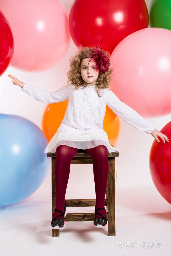 女孩坐在椅子上五颜六色的大气球背景
