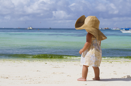 年轻的孩子女孩在夏天帽子的热带海面背景