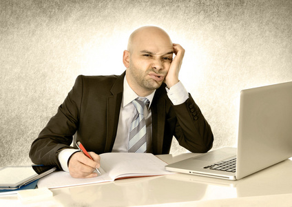 年轻的秃头有吸引力的商业人厌倦了计算机在工作照片