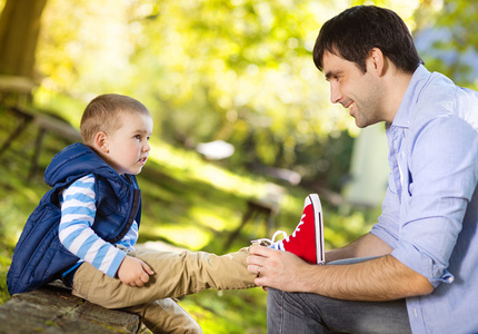 父亲帮助他的儿子去系鞋带