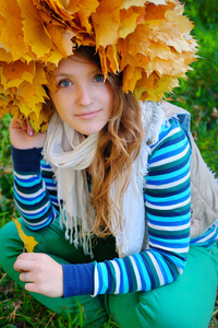 年轻漂亮的女人，在秋天的公园使叶子花环