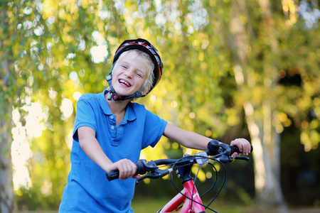 在公园里快乐的学校男孩骑自行车
