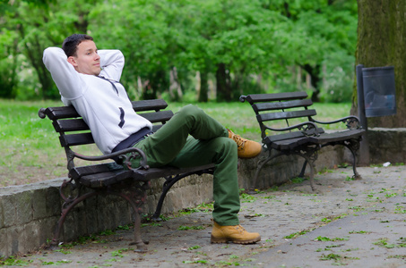 年轻男人坐在公园的长凳上