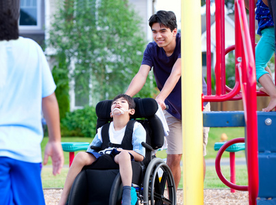 残疾的男孩，在轮椅上享受观看朋友们玩面值