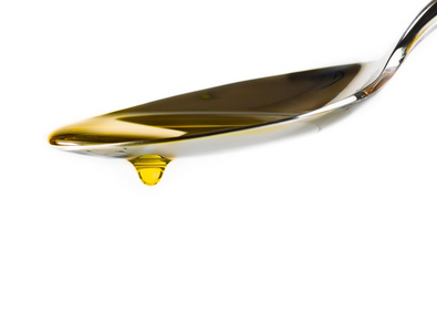 特级初榨橄榄油与放在白色背景上孤立的勺子