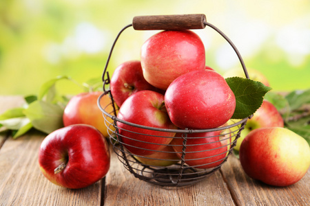甜的苹果在桌子上明亮的背景上的柳条篮子里