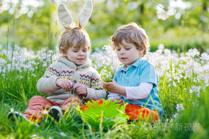 两个小男孩朋友在复活节兔子耳朵期间蛋狩猎