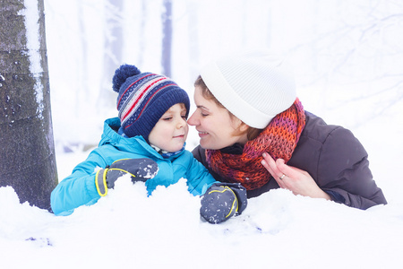 快乐妈妈和她的孩子男孩在冬天玩雪