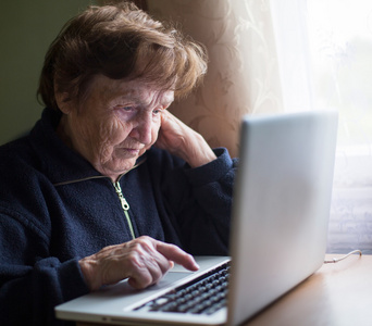 在便携式计算机上键入的老女人