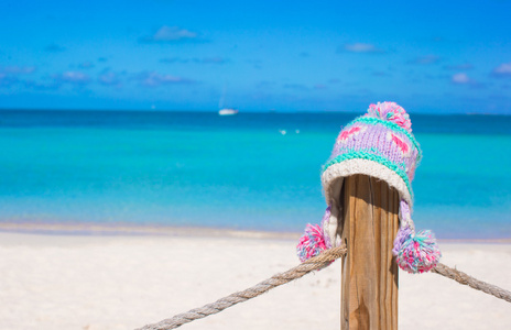 特写温暖针织的帽栅栏在地处热带的海滩上