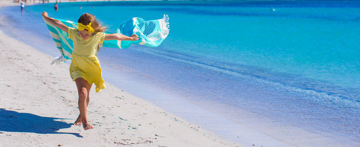 可爱的小女孩有沙滩巾的乐趣