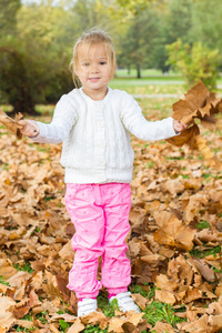 小女孩玩着秋天的树叶